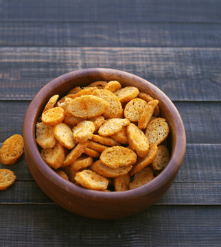 Сroutons from white bread in wooden bowl on a wooden surface of a table.