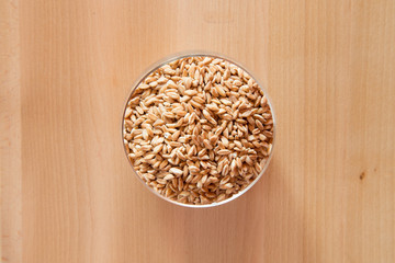 Farro perlato in contenitore di vetro su tavolo di legno