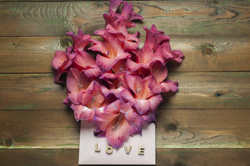 Colorful flowers in envelope, flower delivery concept. The word love a lot of hearts on wooden background. congratulate.