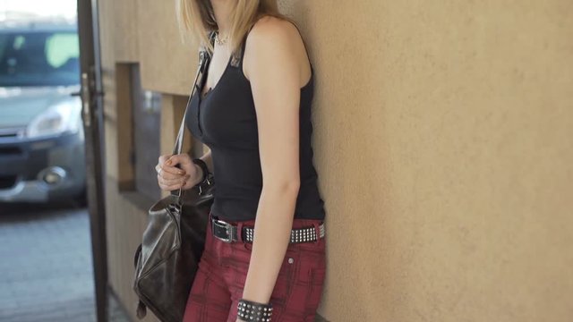 Pretty, punk woman relaxing while leaning on the wall, steadycam shot

