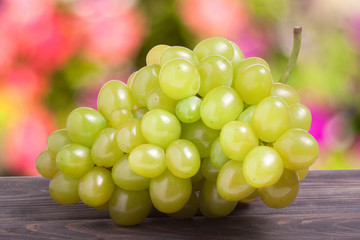 bunch of ripe green grapes on a wooden table with  blurred background