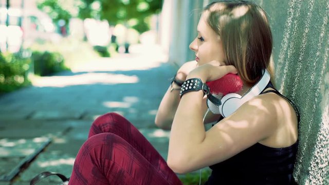 Punk girl sitting on the pathway and using brush to comb her hair

