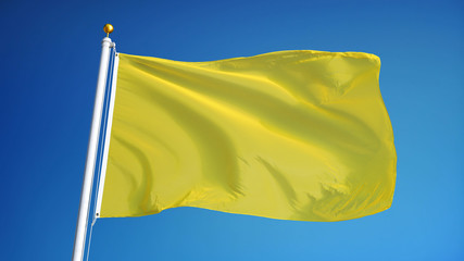 Bright yellow flag waving against clean blue sky, close up, isolated with clipping path mask alpha channel transparency