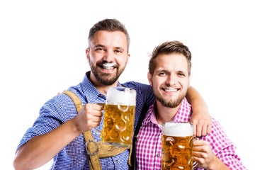 Men in traditional bavarian clothes holding mugs of beer