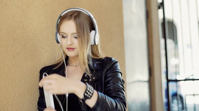 Punk girl listening music on headphones and using tablet
