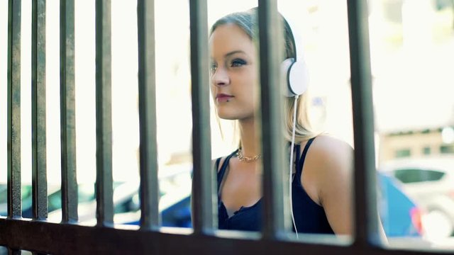 Punk girl listening music smiling to the camera behind the gate
