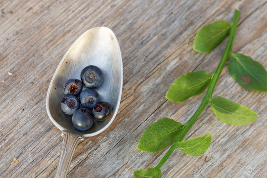 Blueberry in a silver spoone on a wooden table from above in war
