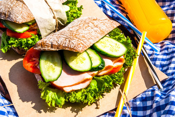 Picnic in the last days of summer: homemade sandwiches of whole grain ciabatta with ham, cheese and...