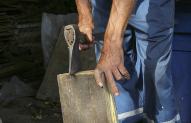 An elderly man with an ax chopping wood. Preparation for the winter period. Firewood.