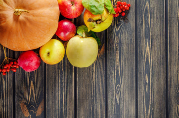 Yellow ripe pumpkin,  leaves, red apples on wooden background. T