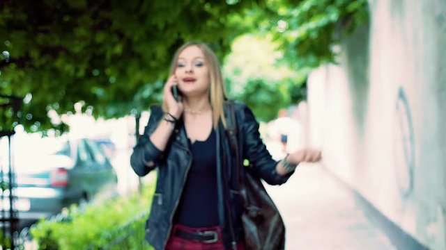 Irritated, punk girl walking on pathway and talking on cellphone
