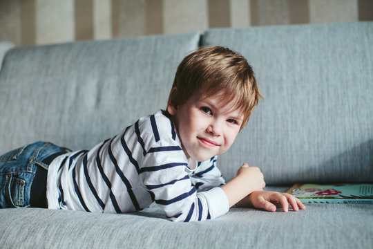 boy reading a book lying on the couch