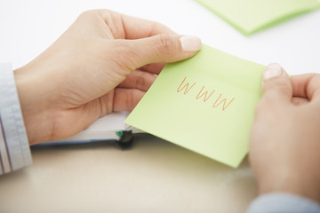 Hands holding sticky note with internet address