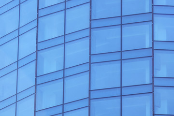The glass facade of a skyscraper with a mirror reflection of sky windows