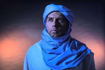 Berber man in night light wearing blue turban with white robe. S