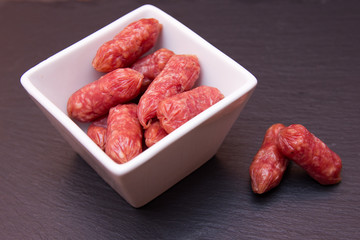 Small sausages on a square bowl on a slate floor