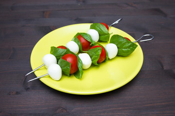 Skewers of mozzarella and tomato on a wooden table
