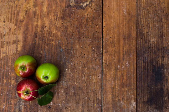 Red ripe apples at dark wooden table.