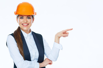 Woman builder in helmet points finger at copy space