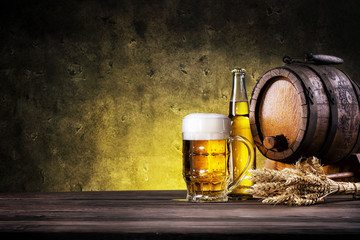 Glass of light beer with bottle and barrel