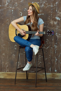Young woman play music on acoustic guitar.