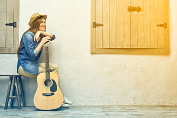 Smiling woman with guitar sitting on street bench
