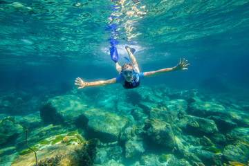 Young female snorkeling in tropical sea. Woman apnea swims in coral reef.