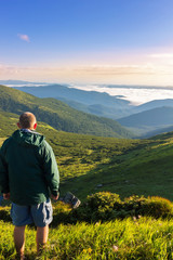 Fototapeta na wymiar Young man standing on the top of mountain and looking at beautiful mountain landscape in sunrise time, Carpathians.