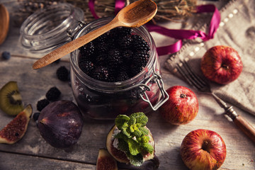 Colorful fruit salad in a jar on rustic wooden background