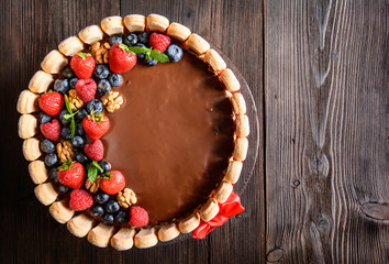 Delicious birthday cake with walnuts filling and strawberries, blueberries and savoiardi biscuit decoration with copy space