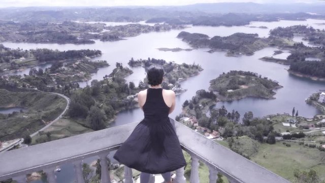 Hispanic woman contemplating the marvelous panoramic view of the islands of Guatape, Colombia. Slow motion