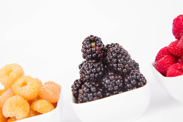 Raspberries and blackberries: bowls of fruit on white background