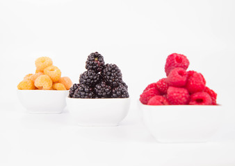 Raspberries and blackberries: bowls of fruit on white background