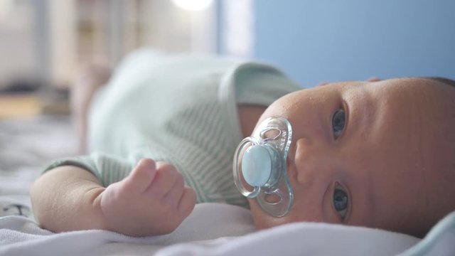 Cute little boy sucking a baby dummy and moving his eyebrows