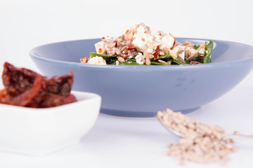 Spinach, dried tomatoes, feta cheese and sunflower seeds salad being eaten with a fork