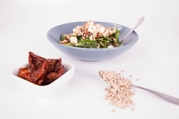 Spinach, dried tomatoes, feta cheese and sunflower seeds salad being eaten with a fork