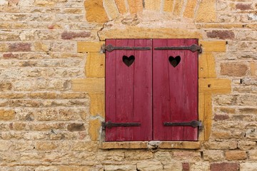 Red window shutters with small hearts in the village of Oingt, Beaujolais, France