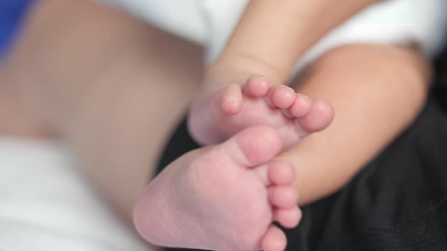 Bare feet of a caucasian newborn child laying in a parent's knees