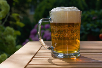 Mug of beer on a table against sunlight