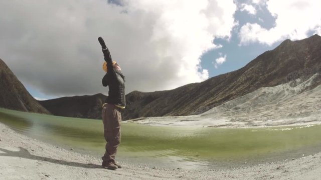 Woman celebrating her success on top of volcano lake, Colombia. 4k