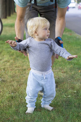 Father hedging their baby, toddler learning to walk