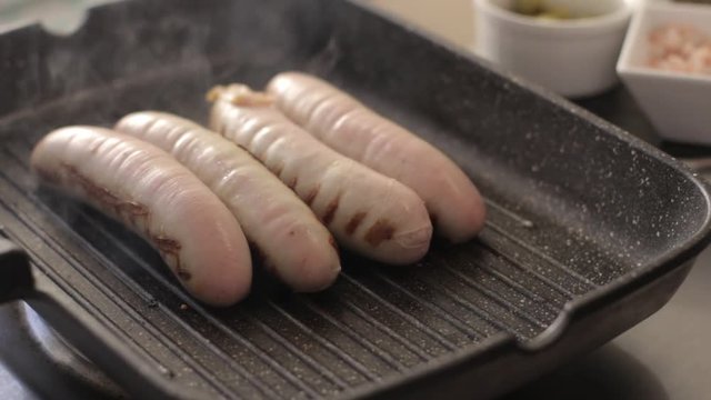 delicious grilled pork sausages rollin on hot grill pan from overhead