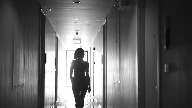 Back view of beautiful young woman walking in hall wearing elegant dress and earrings - black and white video