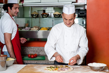 Young male chef preparing delicious pizza