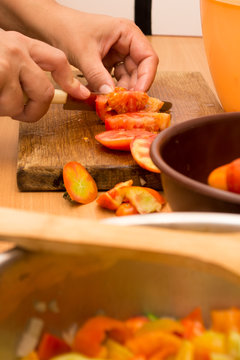 Cutting tomato on a wooden plate