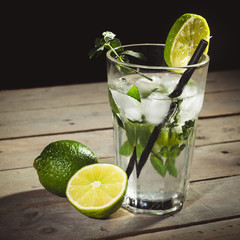 Mojito with limes on wood table with black background.