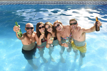happy attractive men and women in bikini having bath at hotel resort swimming pool drinking beer