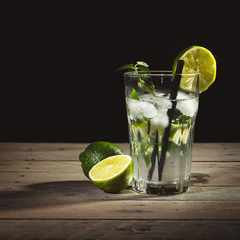 Mojito with limes on wood table with black background.
