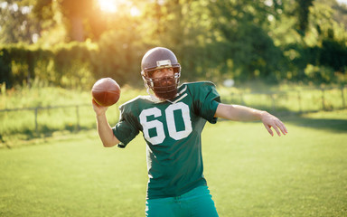 Brutal man with a long beard and mustache in the shape of an American football player with helmet and Ball on the training ground