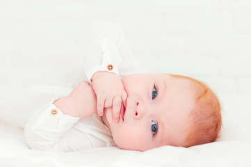 portrait of happy redhead baby boy lying on belly